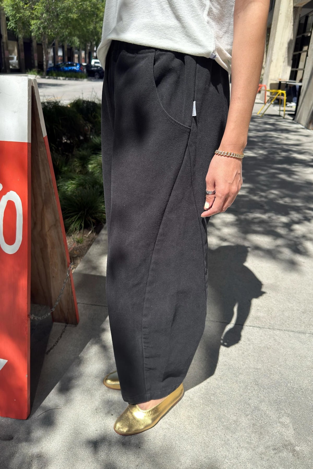 Black Canvas Arc Pants, front street view showing curved legs, styled with a light tee and gold mules