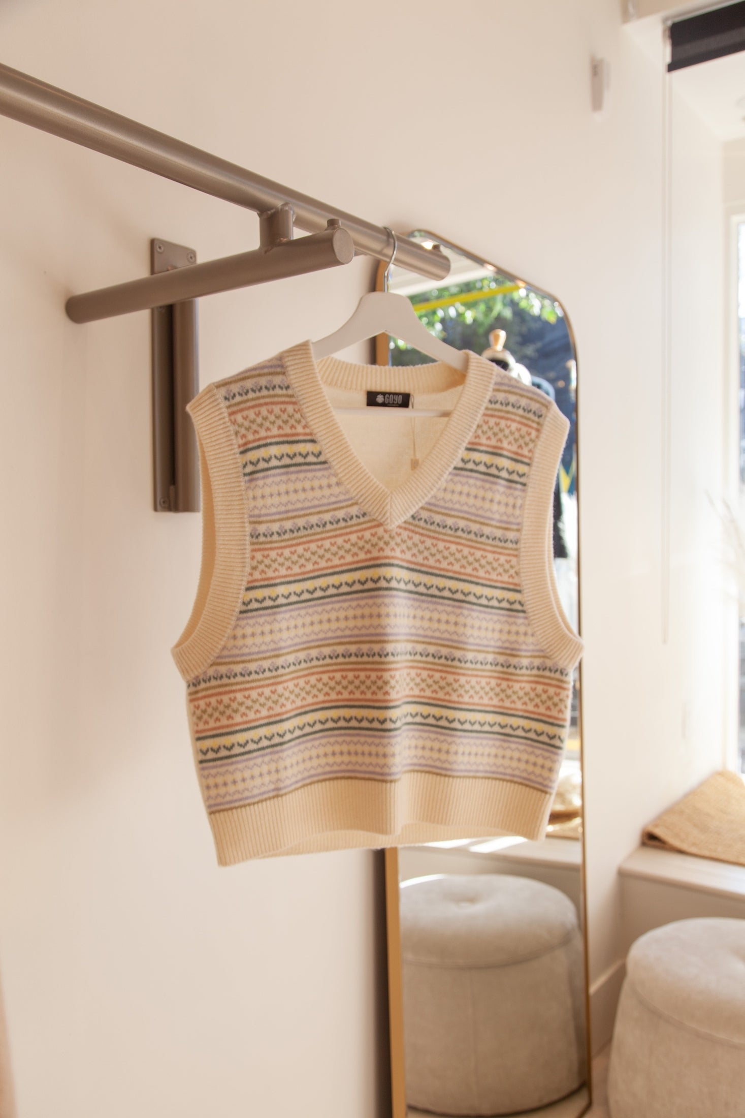 Ivory cashmere boho-chic vest on hanger, featuring a relaxed design and soft, luxurious texture.