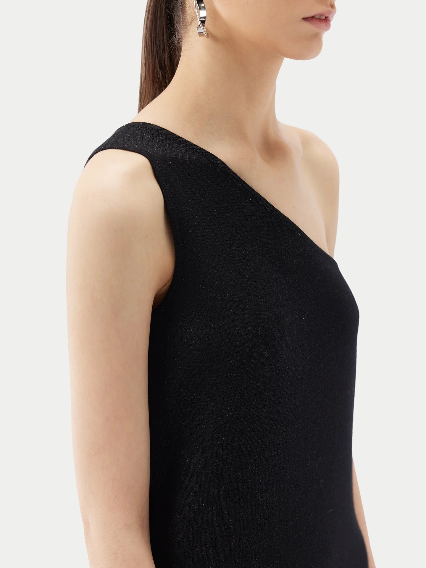 A model wearing a chic black one-shoulder top made from a luxurious silk-cashmere blend.