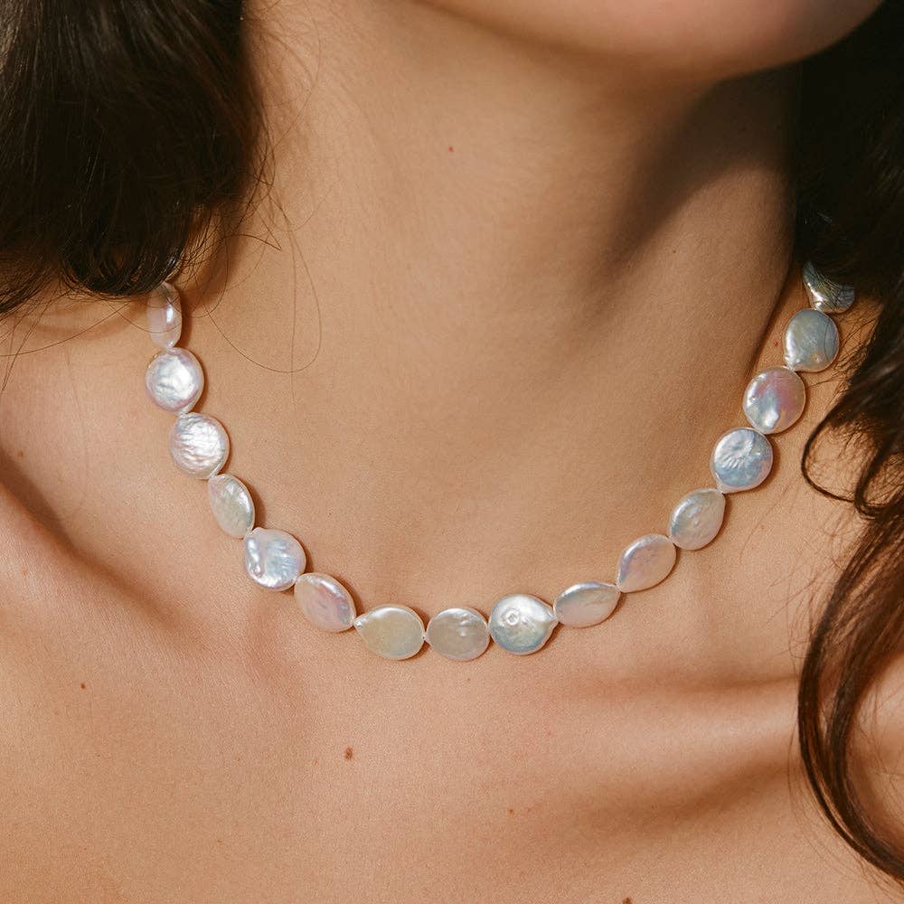 Model wearing a coin-shaped pearl necklace, adding an elegant touch to the look.