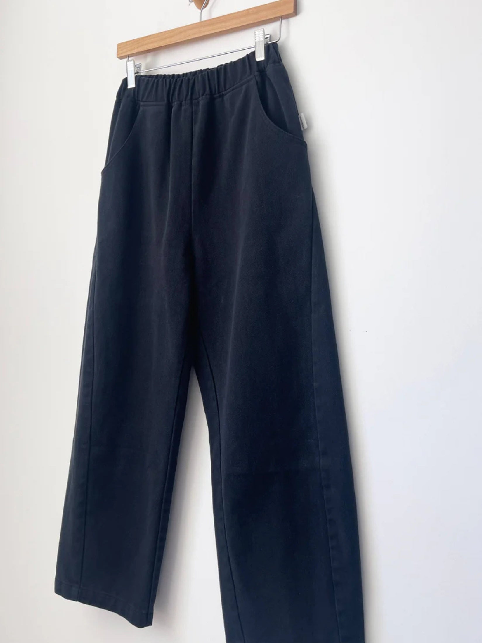 Model wearing black canvas arc pants with a relaxed, modern fit