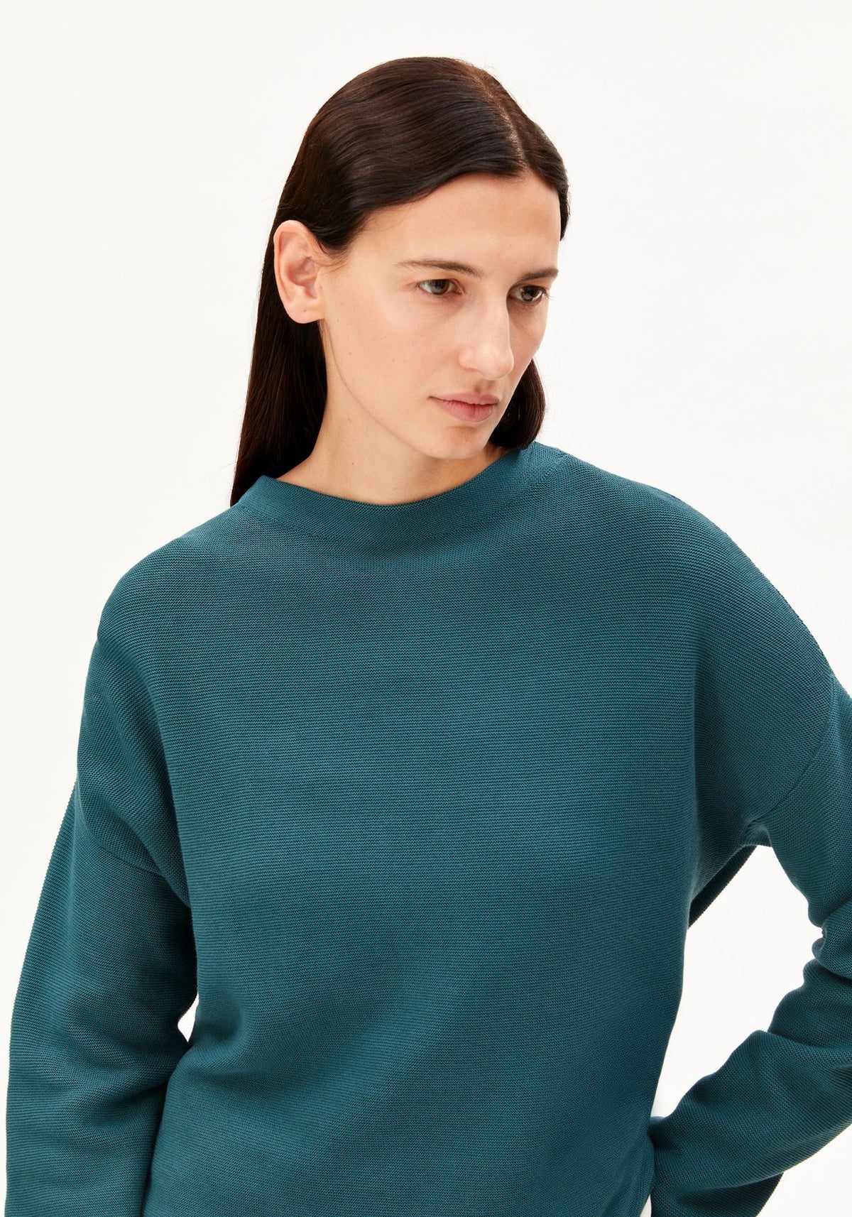 Woman wearing a teal sweater against a white background