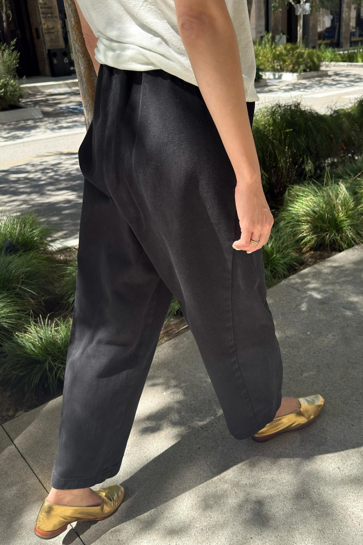 Black Canvas Arc Pants, front street view showing curved legs, styled with a light tee and gold mules