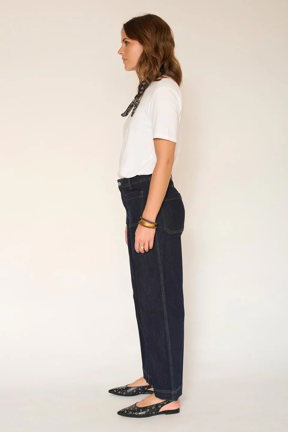 Person wearing a white shirt and dark jeans against a plain background
