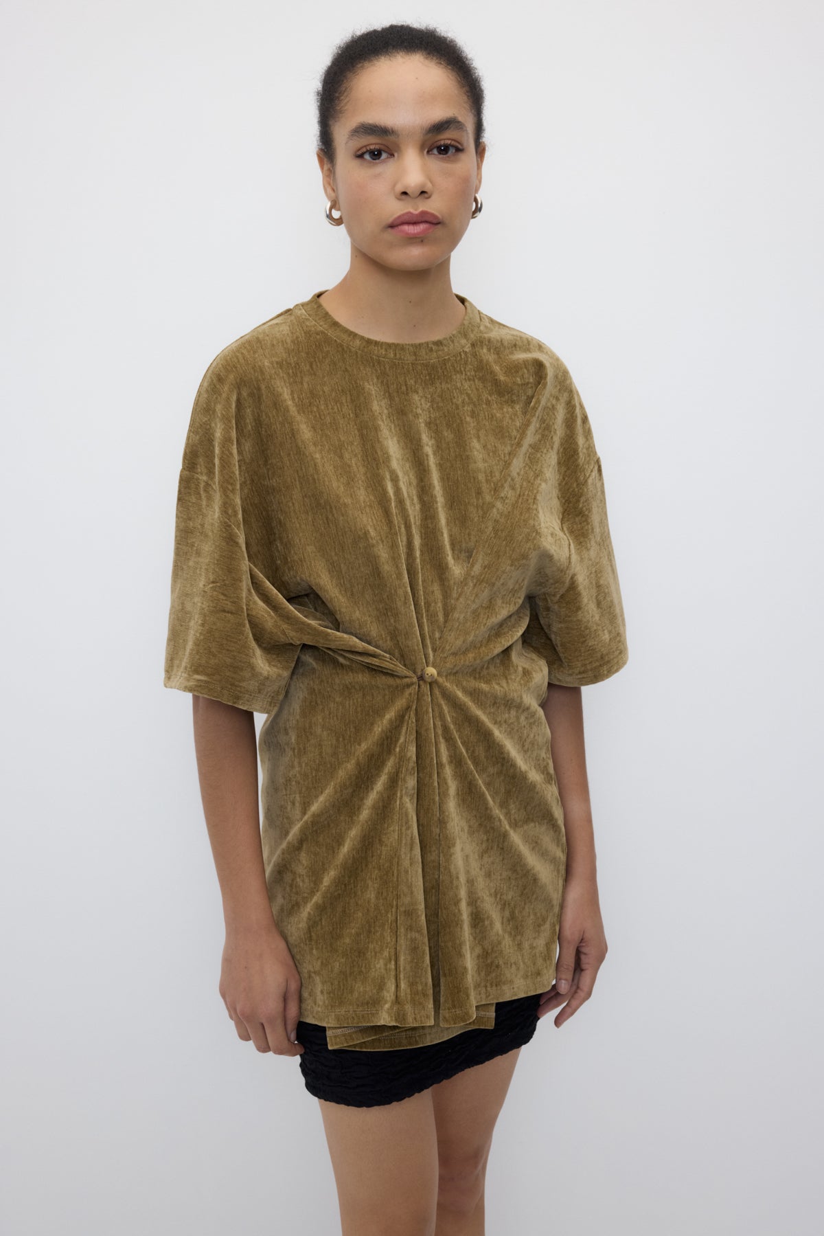 Woman wearing a green velvet dress with a knot detail on a white background