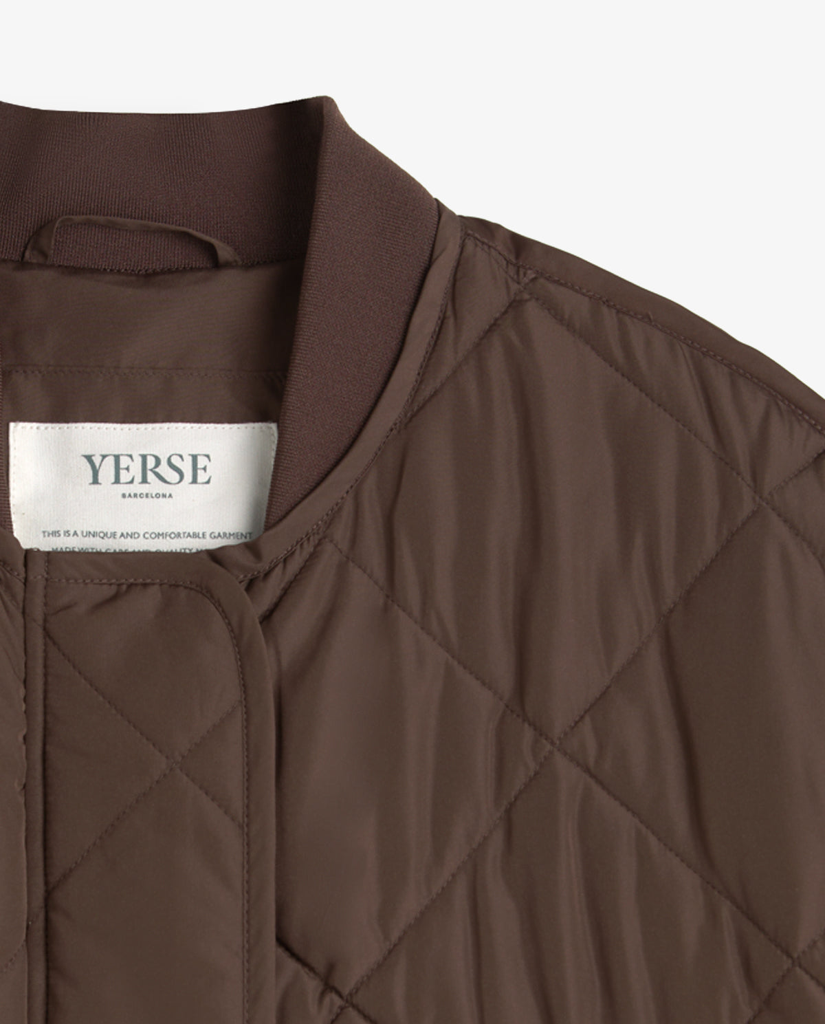 Close-up of a brown quilted jacket with a ribbed collar and a visible YERSE brand label on the inside neck.